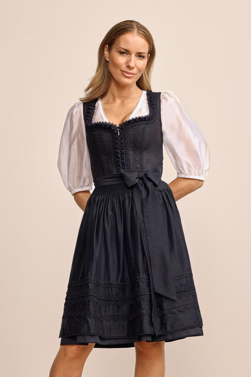 Elegant Verity dirndl in black with tailored cut and 60cm skirt, featuring skirt pockets, front zipper, and subtle apron trim.